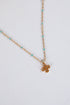 Gold necklace with a small pendant on a light gray background