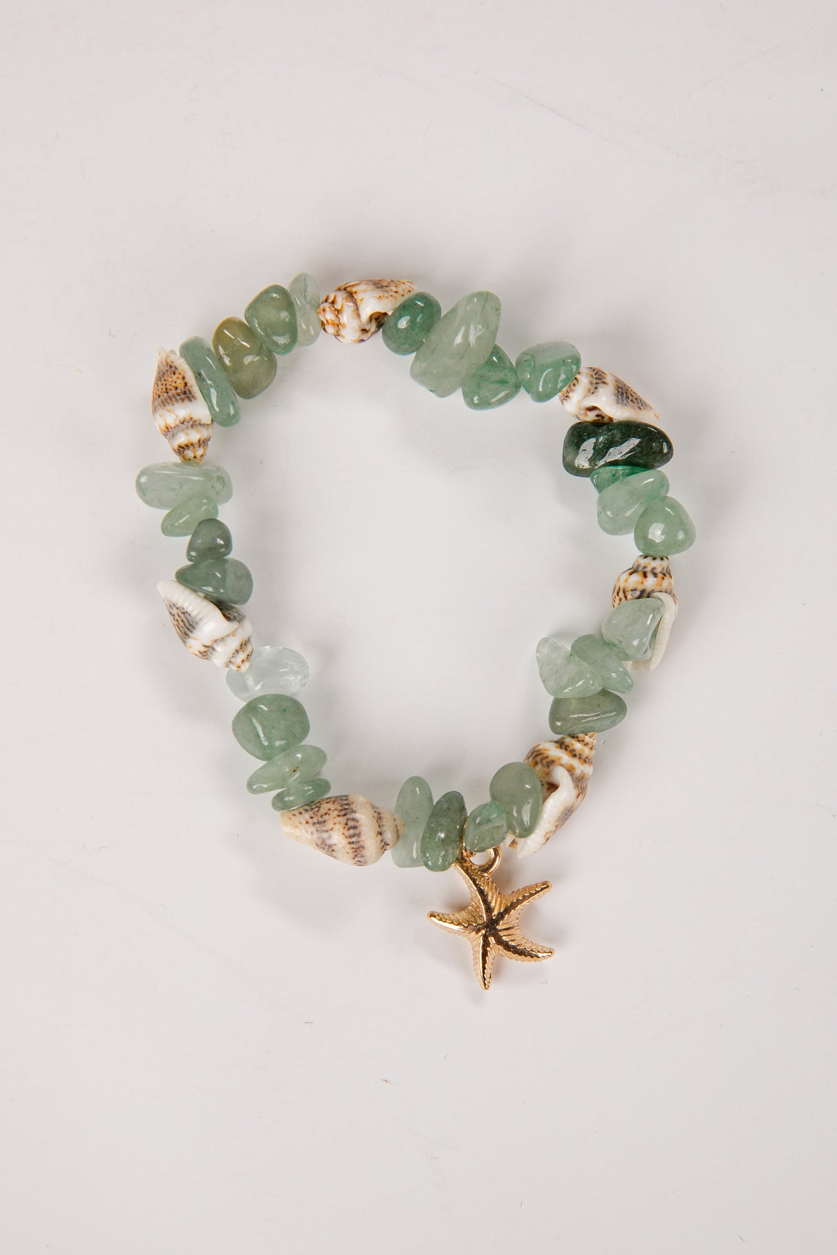 Green beaded bracelet with gold accents and starfish charm on a light gray background