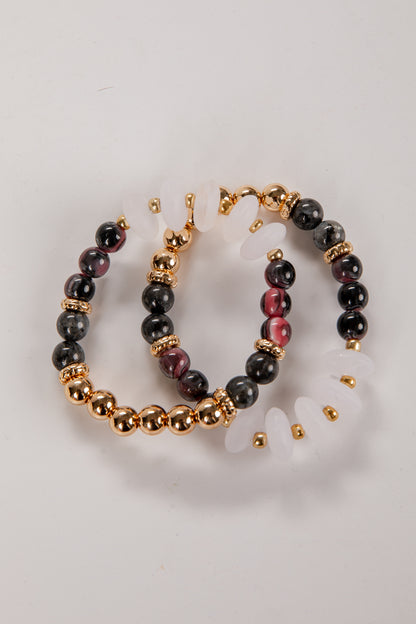 Pair of hoop earrings with black and gold beads on a light gray background