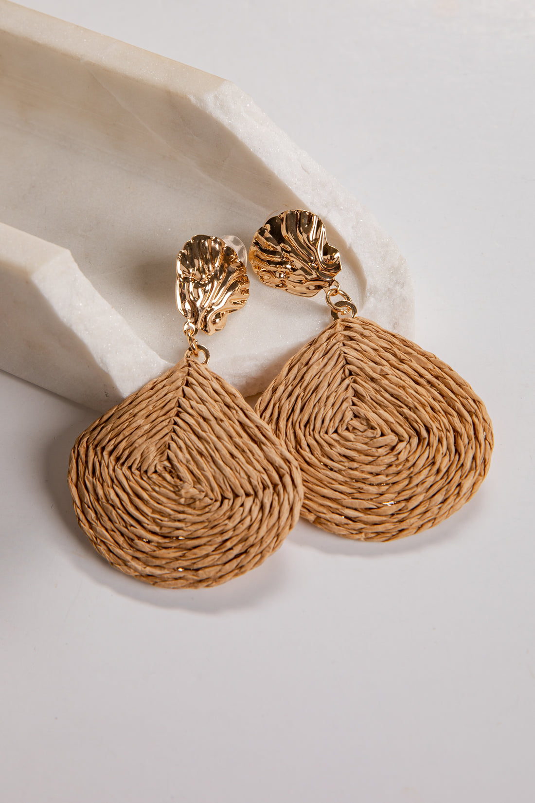 Pair of gold textured earrings on a light background