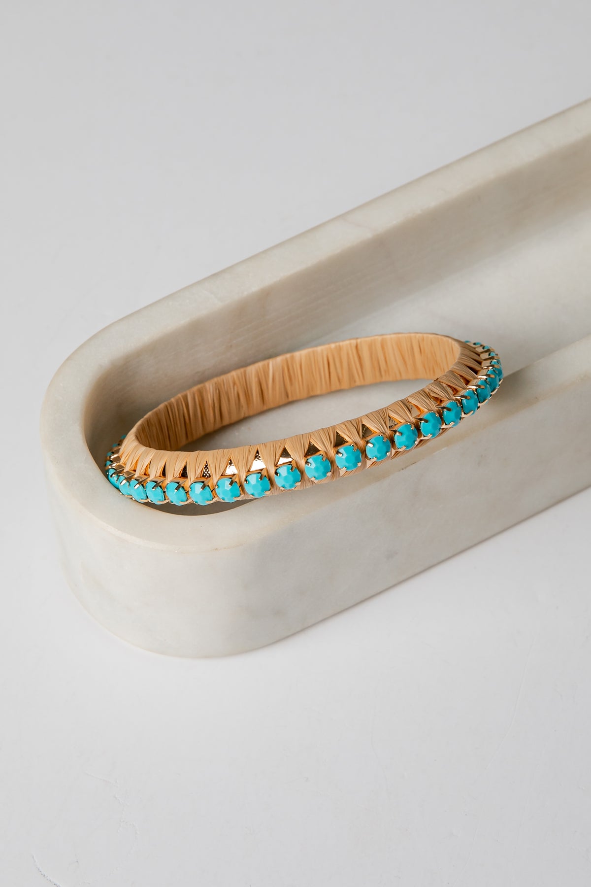 Gold bracelet with turquoise stones on a white surface