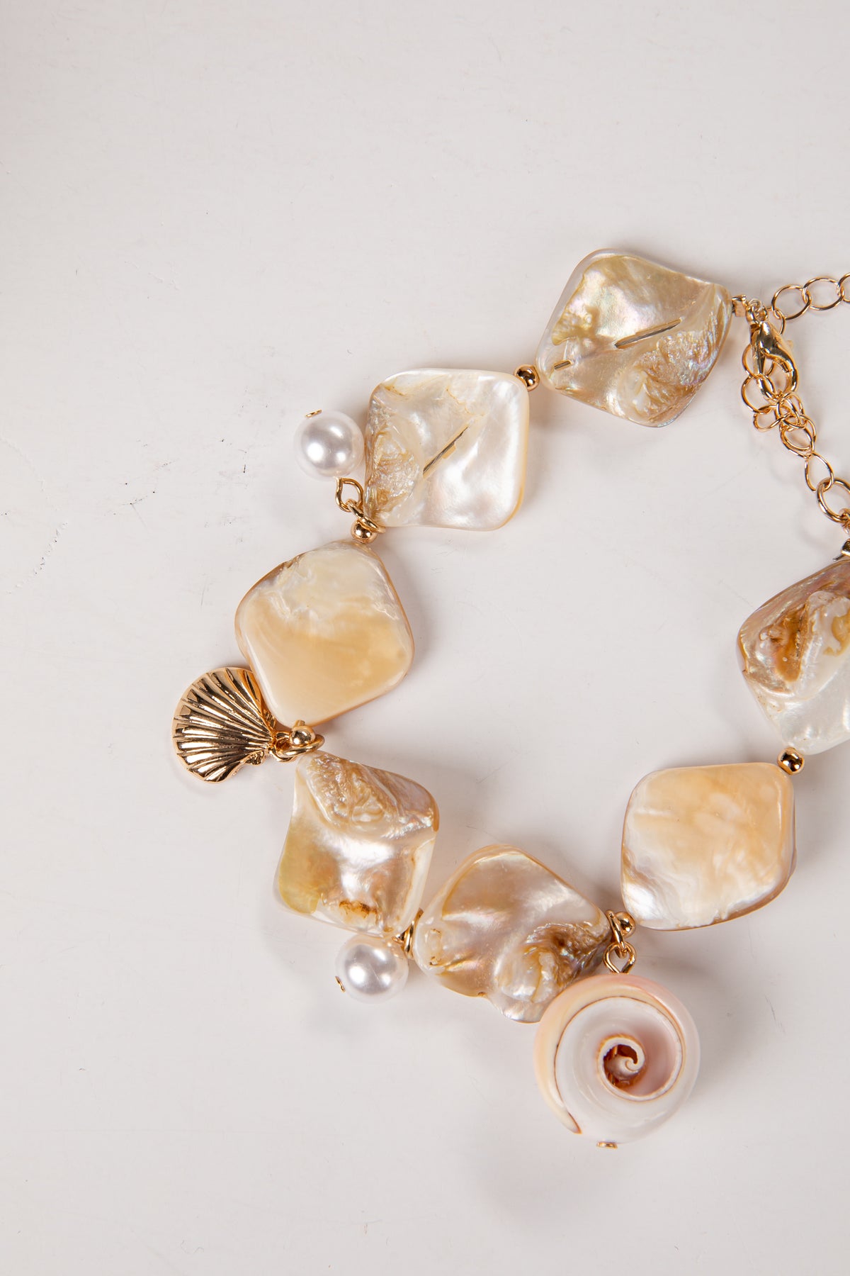 Bracelet with large shell and pearl-like beads on a light background