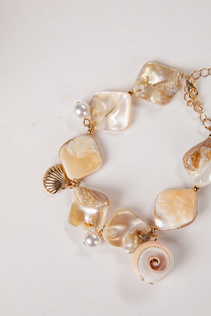 Bracelet with large shell and pearl-like beads on a light background