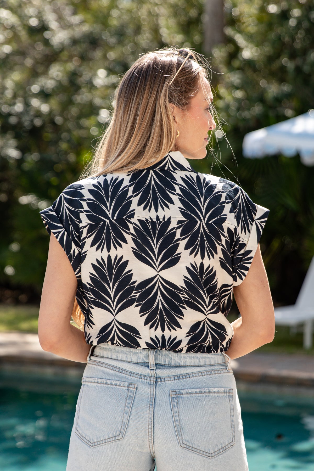 Woman wearing a black and white patterned top by a poolside