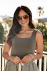Woman wearing sunglasses and a sleeveless top with a blurred outdoor background