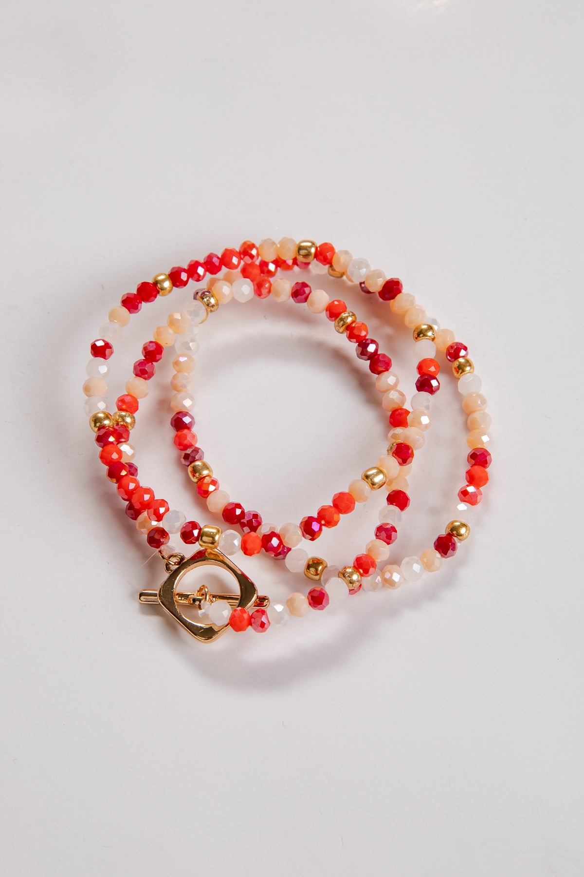 Beaded bracelet with orange, gold, and white beads on a light gray background
