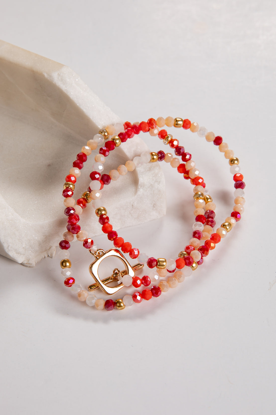 Beaded bracelet with red and gold accents on a white background