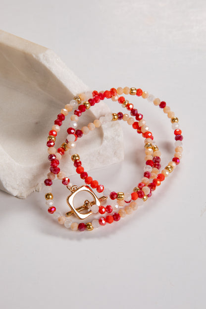 Beaded bracelet with red and gold accents on a white background