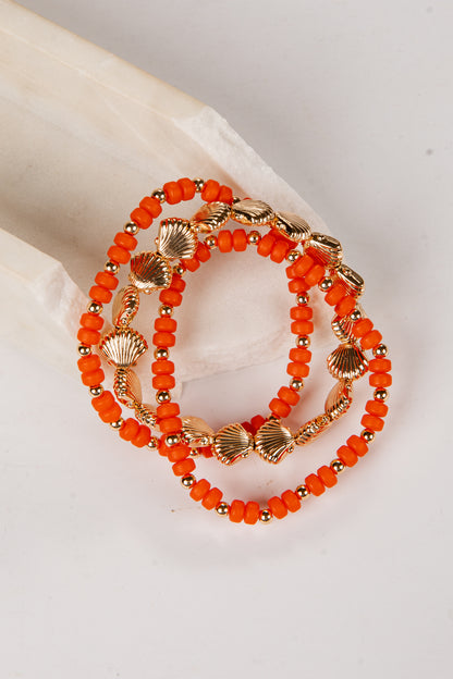 Orange beaded bracelet with gold accents on a light background