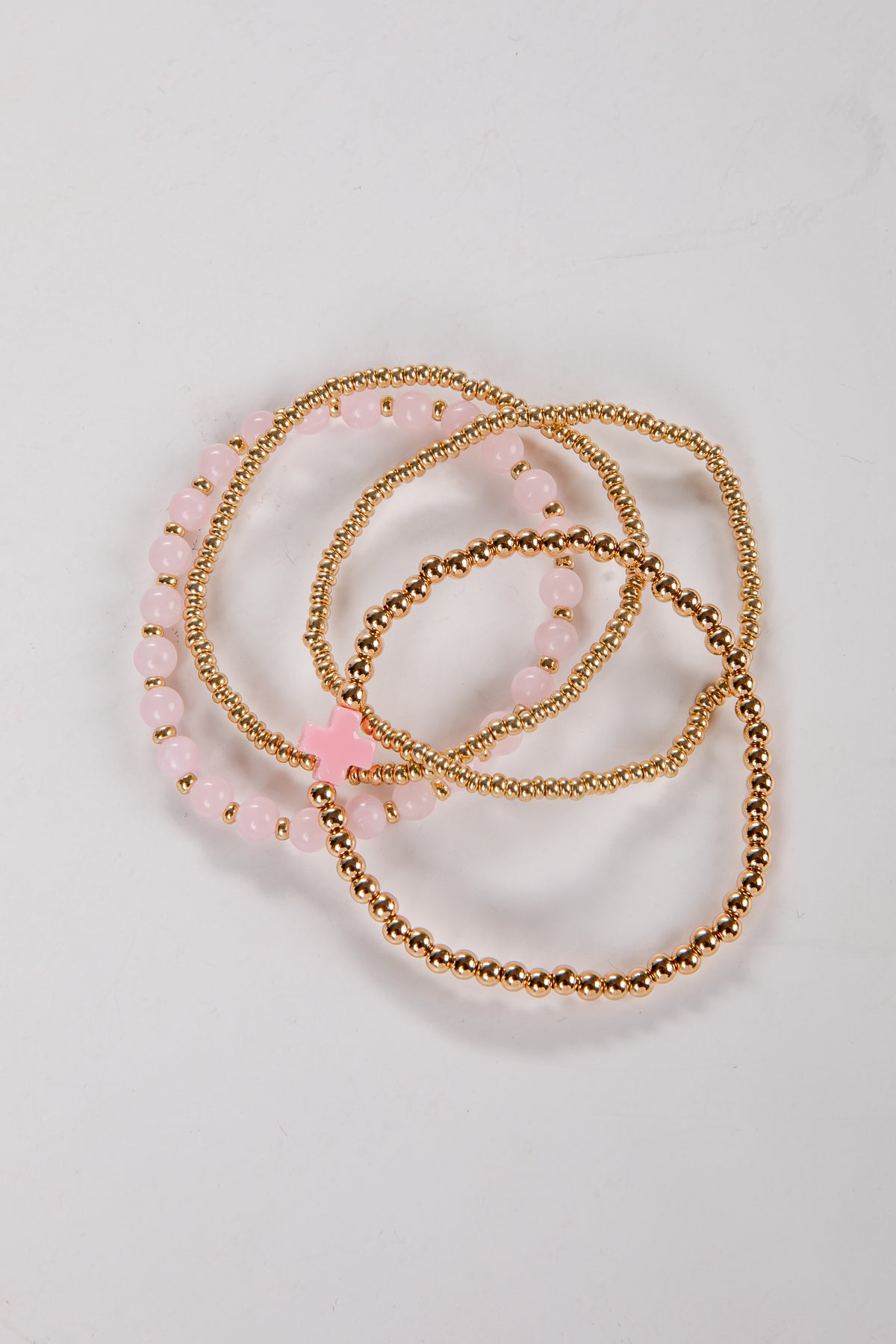 Set of gold and pink beaded bracelets on a light background