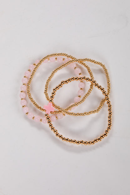 Set of gold and pink beaded bracelets on a light background