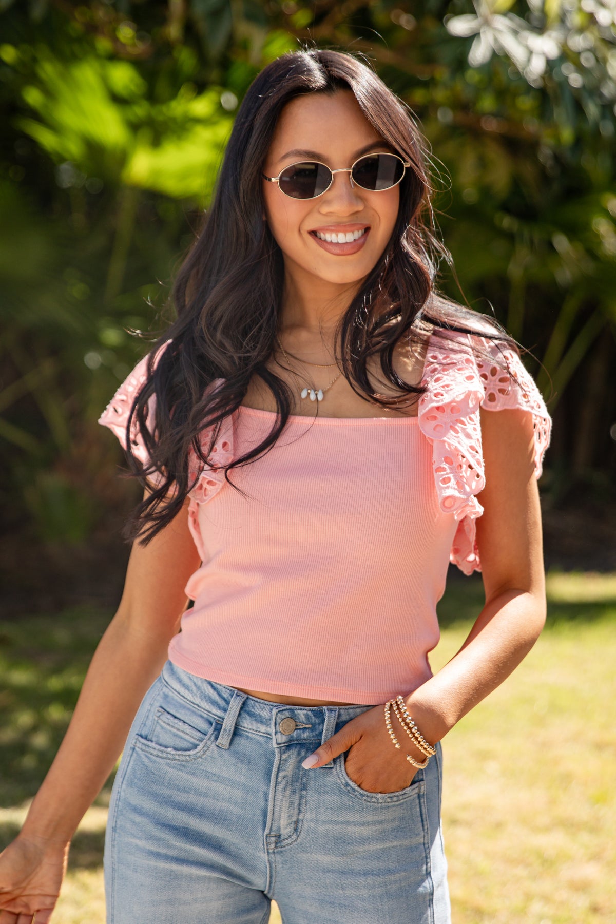 Woman in pink short-sleeve top and denim jeans outdoors.