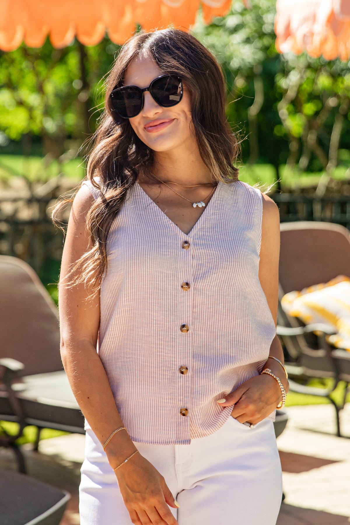 Woman wearing sunglasses and a sleeveless button-up top outdoors