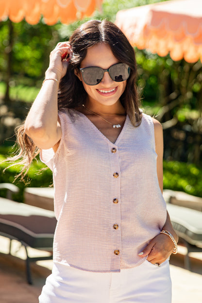 Woman wearing sunglasses and a sleeveless button-up shirt outdoors