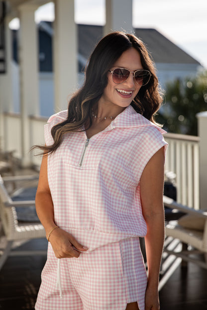 woman wearing a pink gingham quarter zip collared tank top
