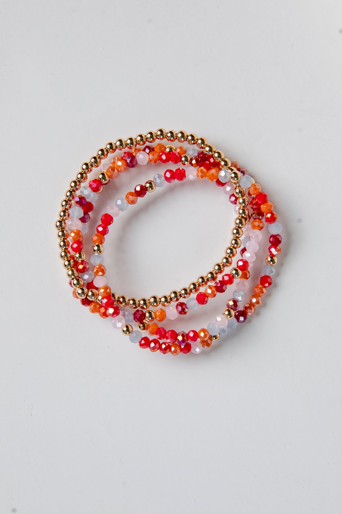 Set of beaded bracelets with red and gold accents on a light gray background