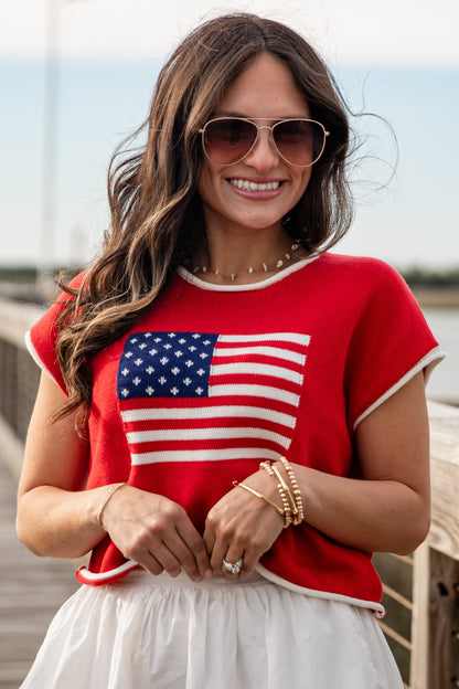 Woman wearing a red shirt with an American flag design outdoors.