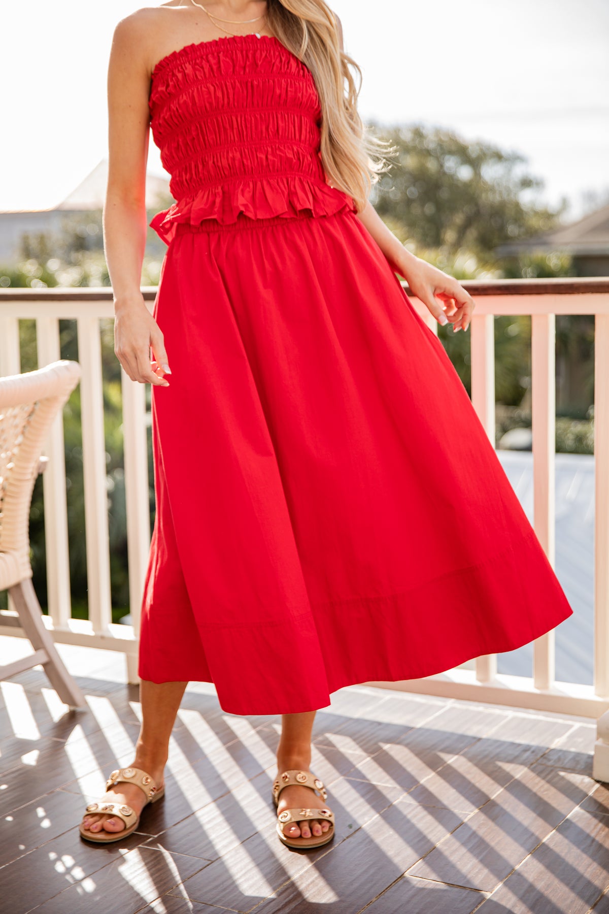 Woman wearing a red strapless dress on a balcony