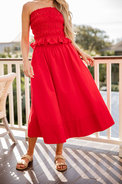 Woman wearing a red strapless dress on a balcony