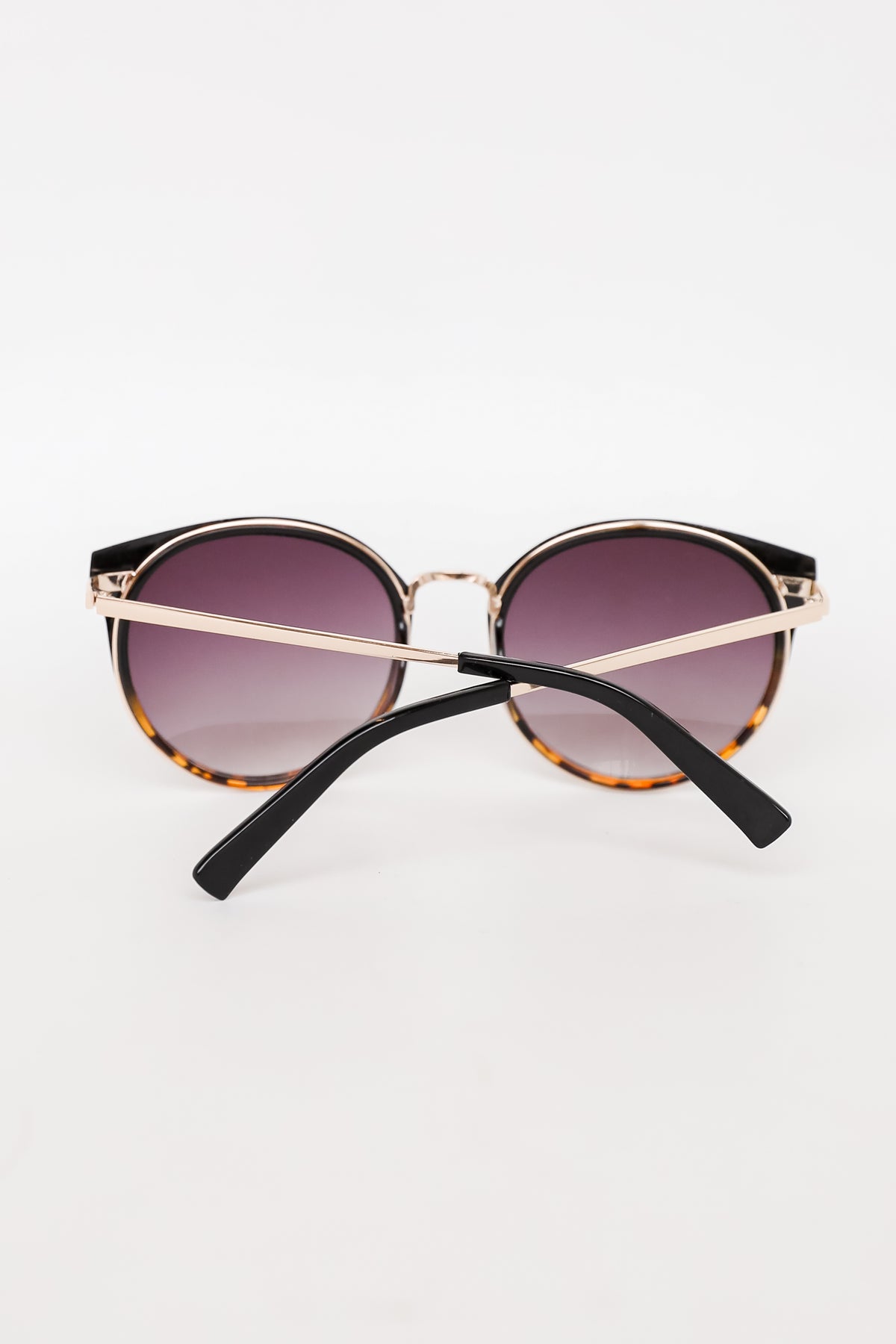 Sunglasses with gold frame and black arms on a white background