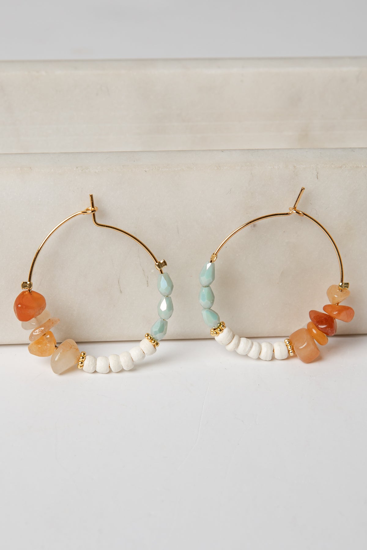 Pair of hoop earrings with colorful beads on a light background