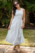 Woman in a light blue dress standing outdoors with greenery in the background