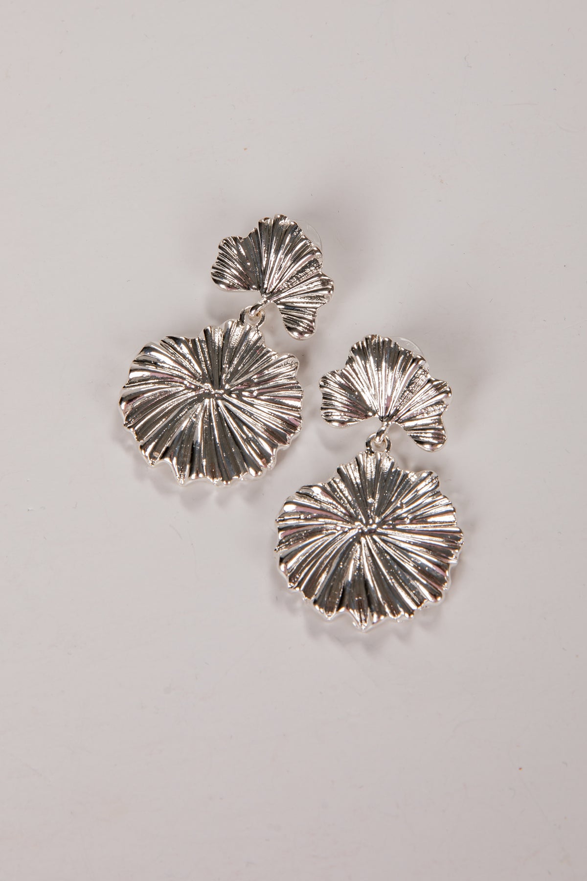 Silver earrings with a textured design on a light gray background