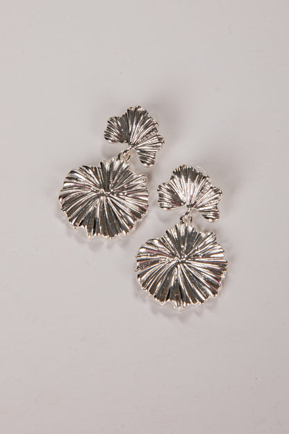 Silver earrings with a textured design on a light gray background