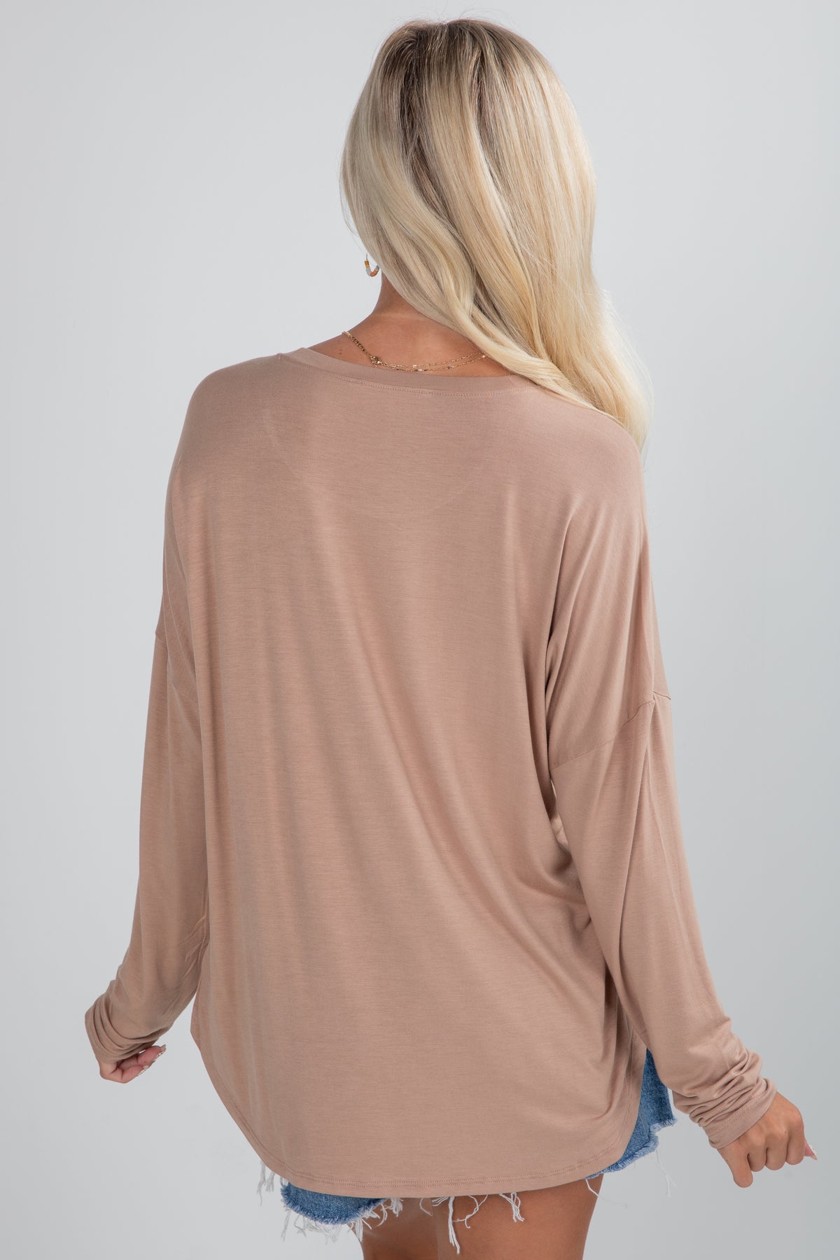 Woman wearing a beige long-sleeve top on a plain background
