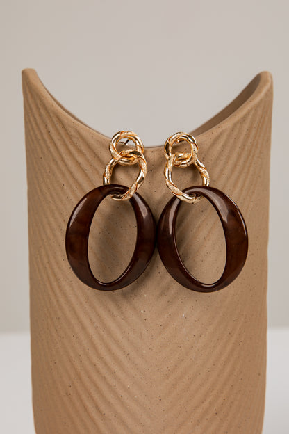 Wooden hoop earrings with gold loops on a wooden stand.