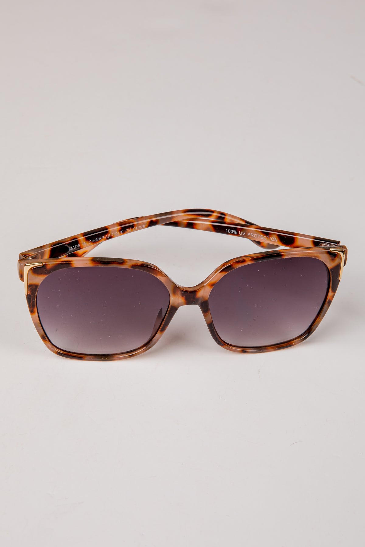 Tortoiseshell sunglasses with dark lenses on a light gray background