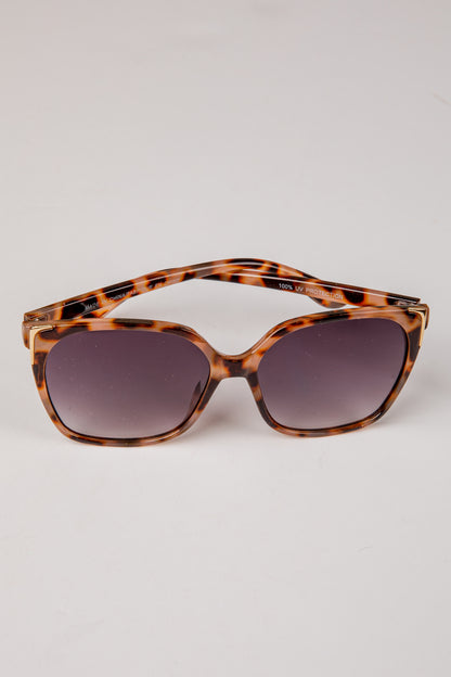 Tortoiseshell sunglasses with dark lenses on a light gray background