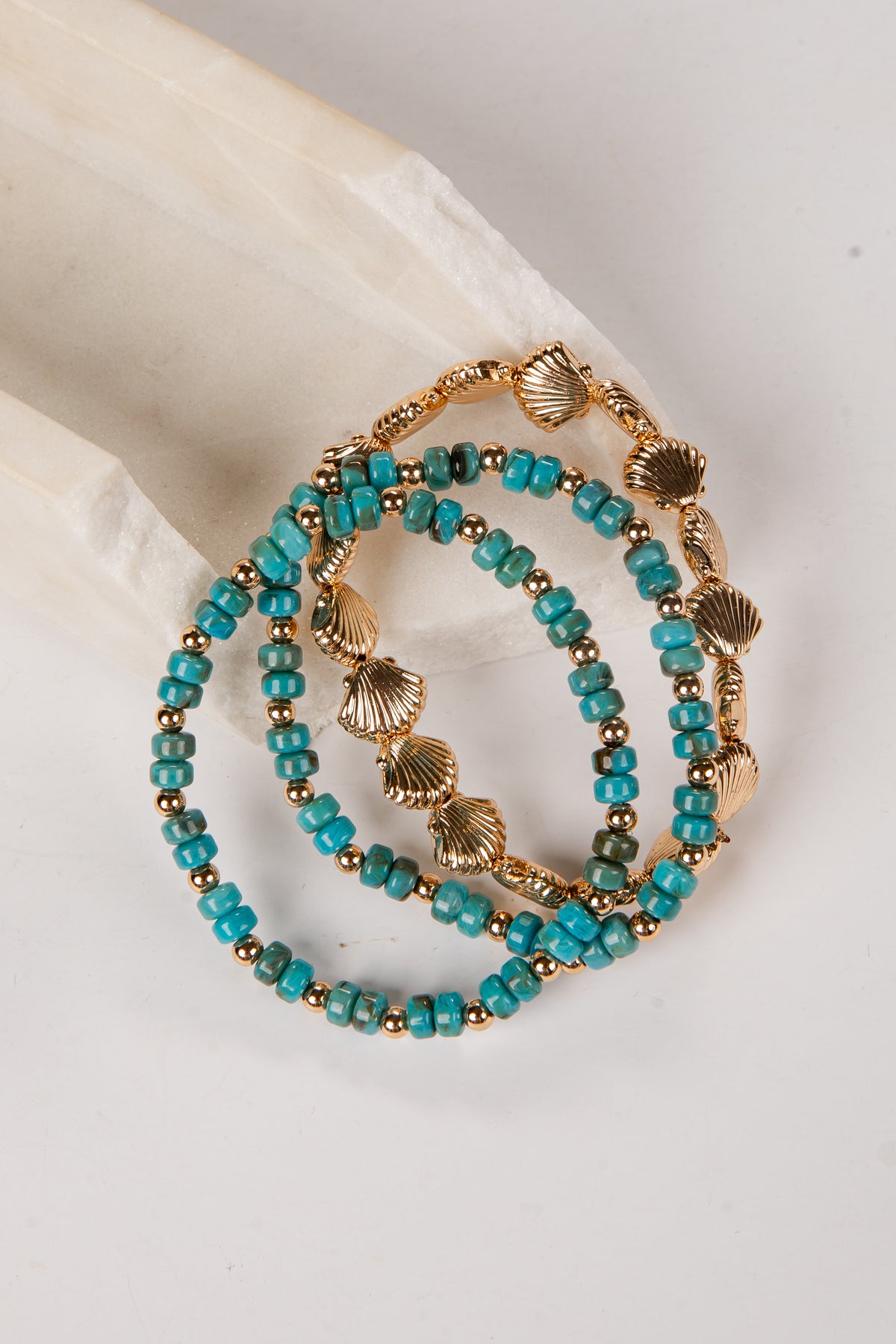 Turquoise beaded bracelet with gold accents on a white surface