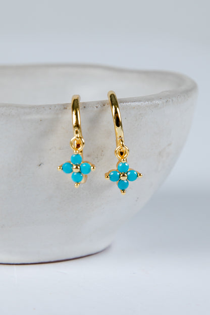 Gold earrings with turquoise stones on a white background