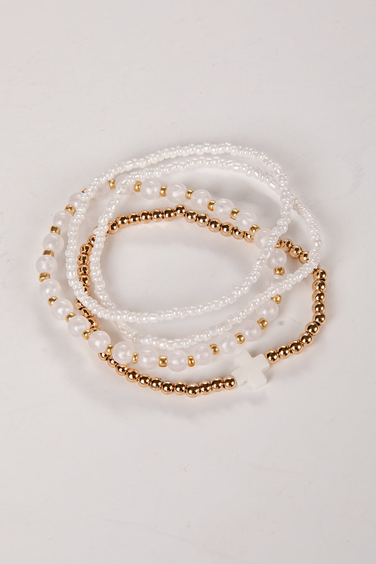 Set of pearl and gold beaded bracelets on a light background