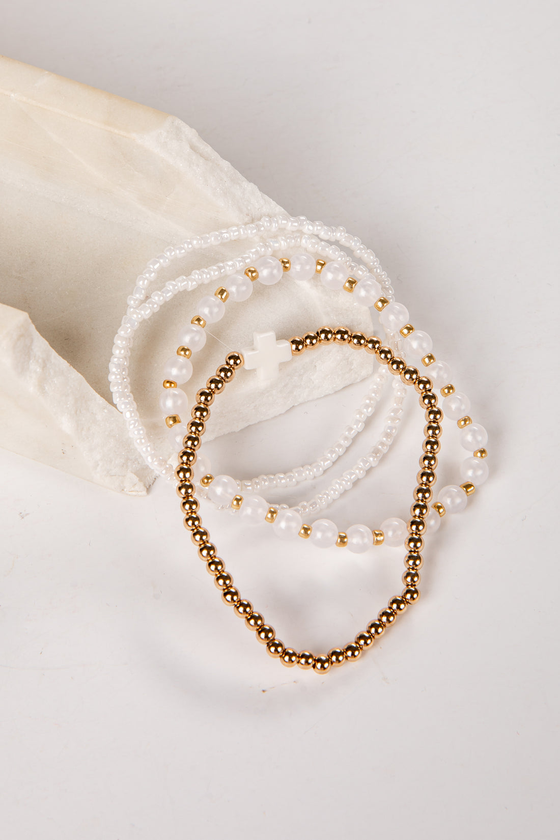 Two pearl and gold beaded bracelets on a white surface