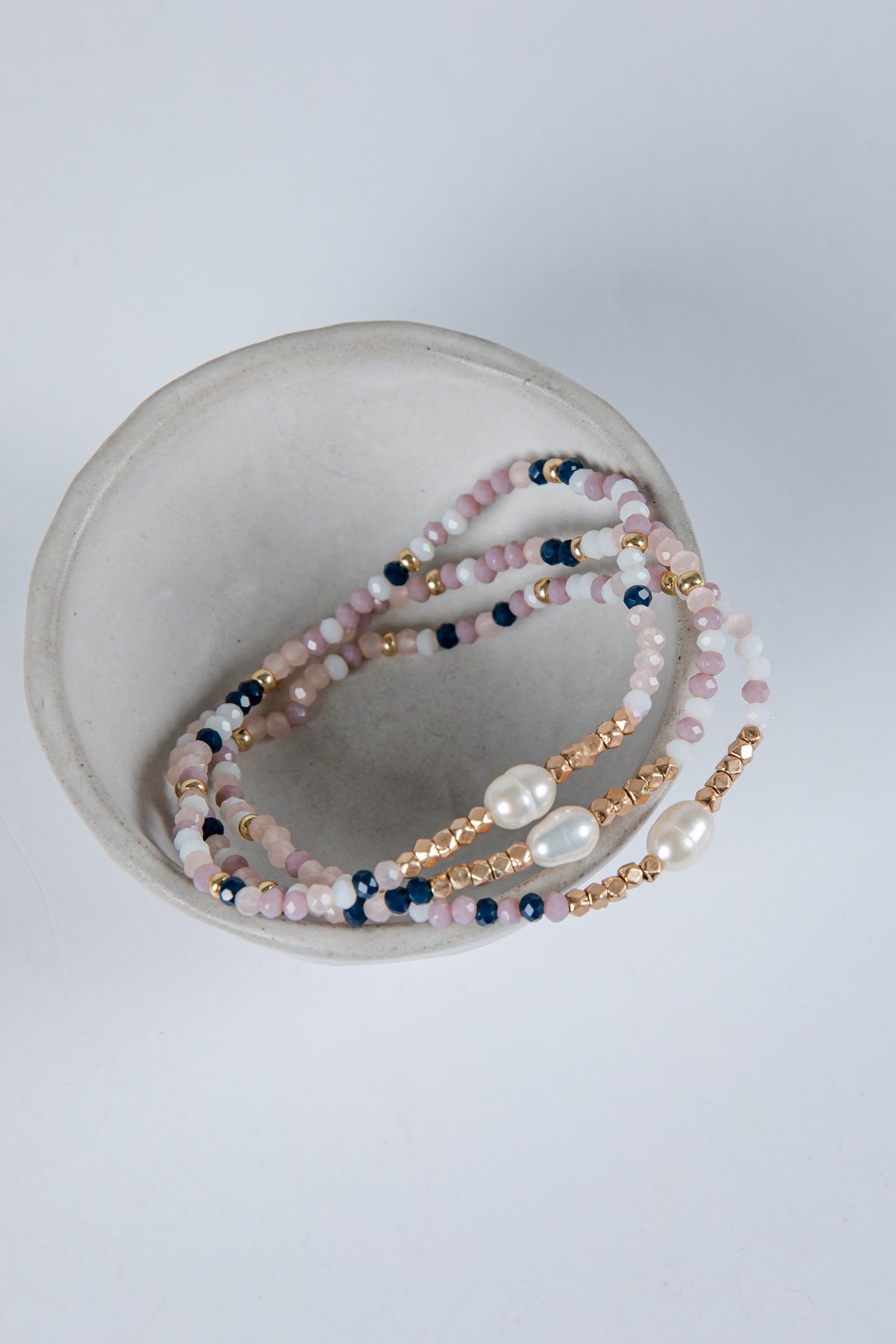 Set of beaded bracelets with pearls on a light gray background