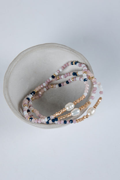 Set of beaded bracelets with pearls on a light gray background