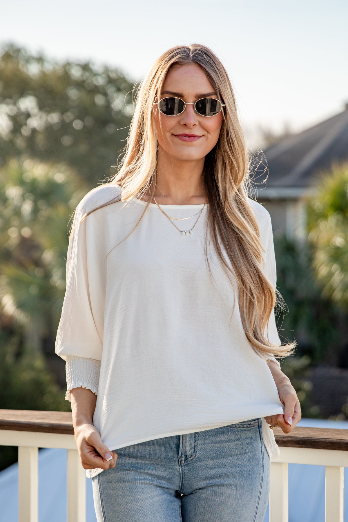 Woman wearing a white blouse and sunglasses outdoors