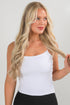 Woman wearing a white tank top against a plain background