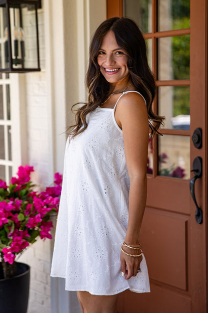 Woman in a white dress standing in front of a door with pink flowers.