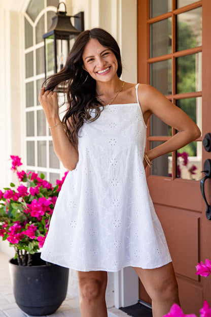 Woman in a white dress standing in front of a door with pink flowers.