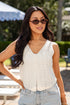 Woman wearing a white sleeveless top and sunglasses outdoors