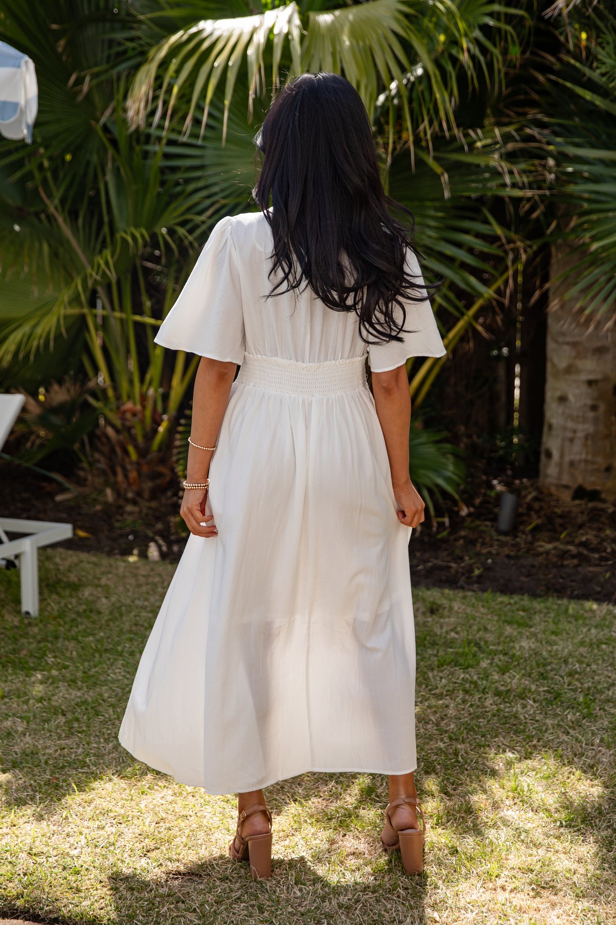 Woman in a white dress standing in a garden with greenery around