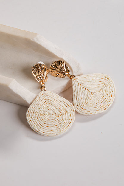 Pair of gold and cream earrings on a light background