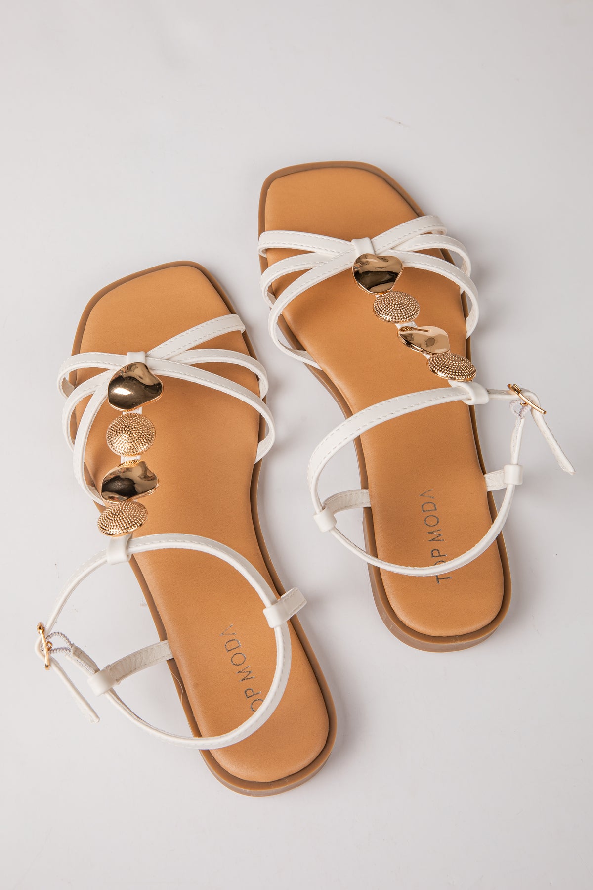 Pair of tan sandals with white straps on a light gray background