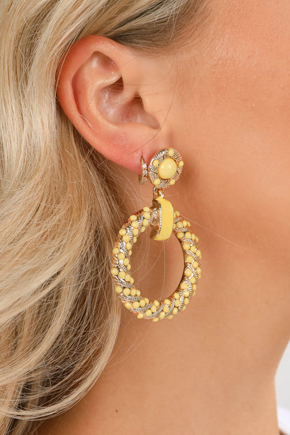 Close-up of a person wearing yellow hoop earrings with a blurred background