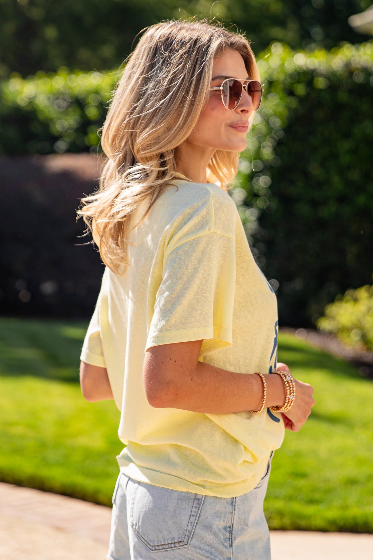 Woman wearing a light yellow shirt and sunglasses outdoors
