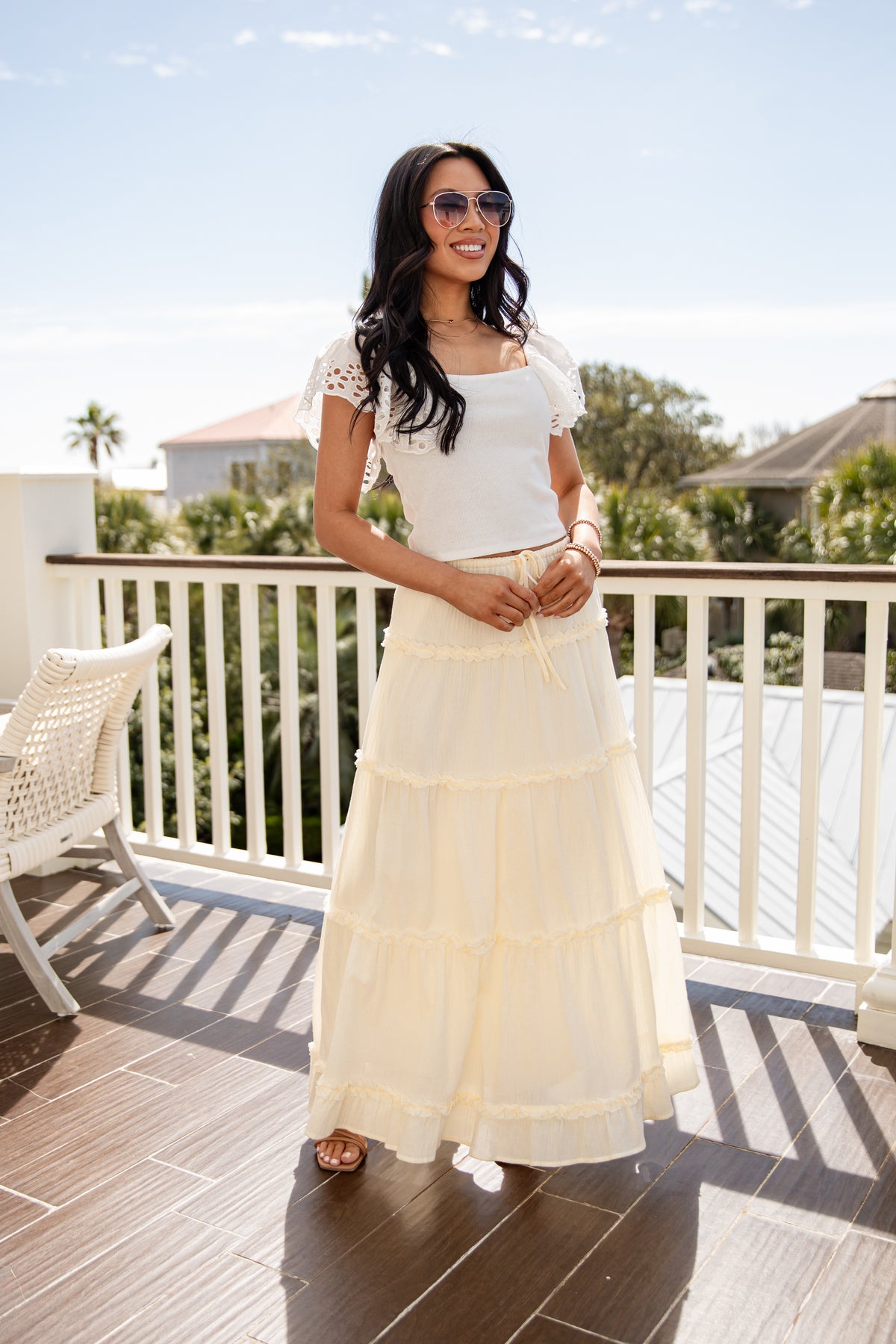 Woman in a white dress standing on a balcony with a scenic background