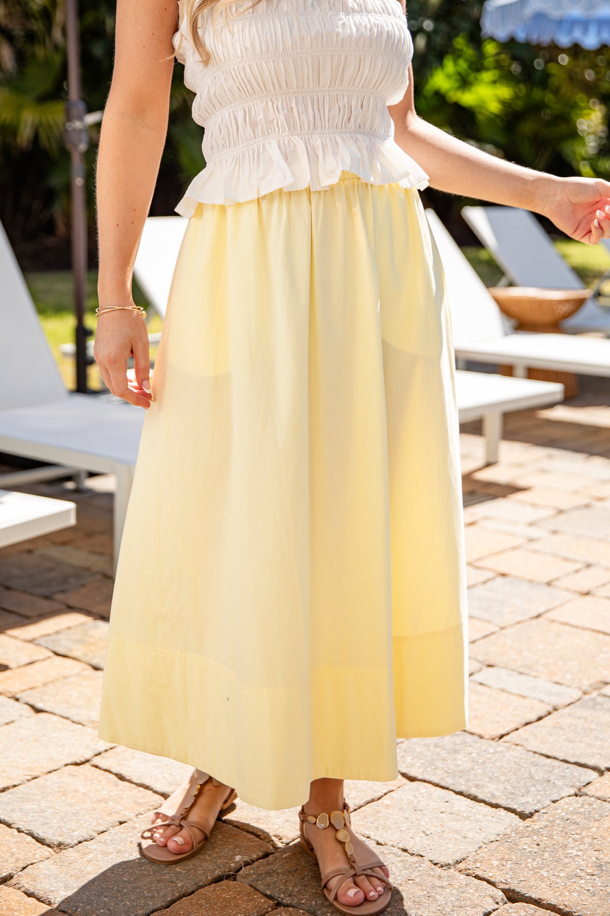 Person wearing a white top and yellow skirt on a patio